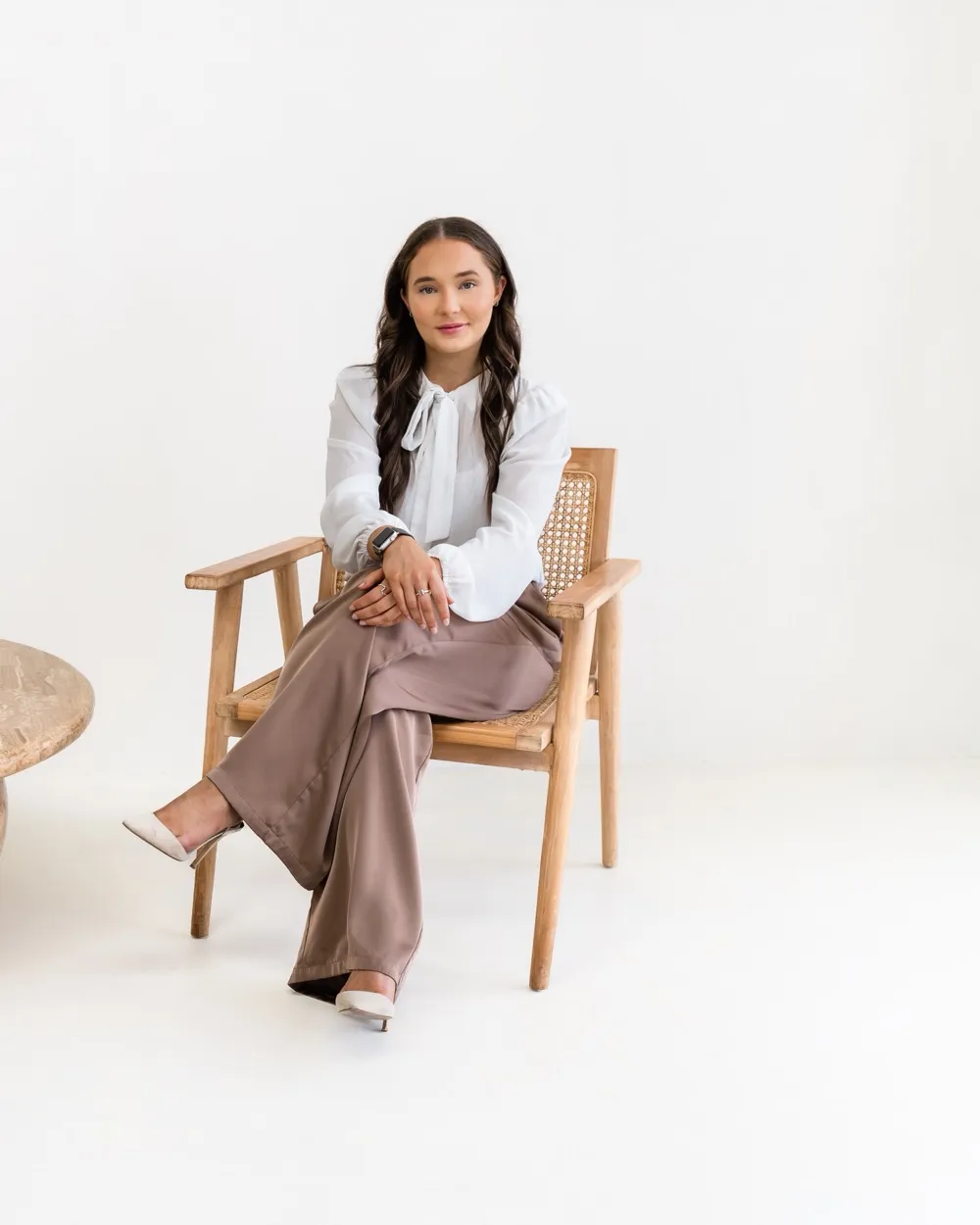 Tayla Jones, seated in a cane armchair beside a low timber table