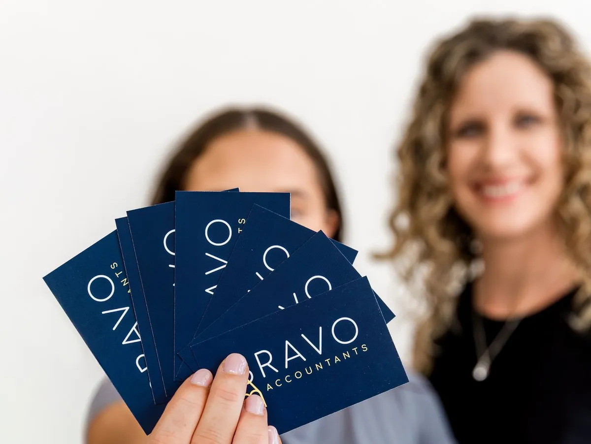 Bravo Accountants brand cards held up, the office out of focus behind them